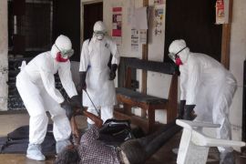 Health workers in protective gear move the body of a person that they suspect dyed form the Ebola virus in Monrovia, Liberia, Tuesday, Sept. 16, 2014. The number of Ebola cases in West Africa could start doubling every three weeks and it could end up costing nearly $1 billion to contain the crisis, the World Health Organization warned Tuesday. (AP Photo/Abbas Dulleh)