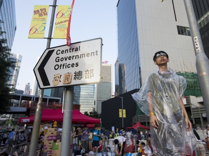 A student stands next to a sign, which originally read "Central Government Offices" and was modified to "Citizens' Headquarters", as riot police stand guard during a rally outside the government headquarters in Hong Kong September 28, 2014. Violent clashes between Hong Kong riot police and students galvanized tens of thousands of supporters for the city's pro-democracy movement and kick-started a plan to lock down the heart of the Asian financial centre early on Sunday. REUTERS/Tyrone Siu (CHINA - Tags: POLITICS CIVIL UNREST EDUCATION)
