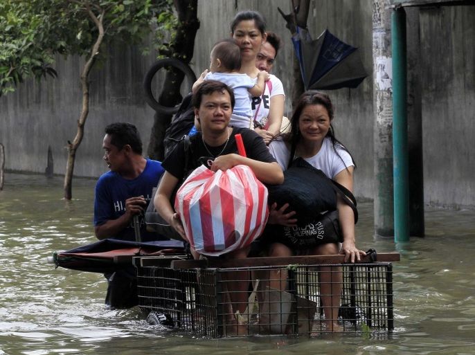 People ride in a improvised bicycle trolley while travelling down a flooded street after Tropical Storm Fung-Wong battered Cainta, Rizal province, east of Manila September 20, 2014. Storm Fung-Wong churned towards Taiwan on Saturday after killing at least five people in the Philippines, and forcing some 200,000 people into temporary shelter, including in the capital Manila, to escape massive flooding. Fung-Wong, with winds of 95 kph (59 mphro) and gusts of 120 kph, slammed in the northern tip of the Philippines on Friday, cutting power in many areas and soaking rice and corn farms and bringing the capital to a near standstill. REUTERS/Romeo Ranoco (PHILIPPINES - Tags: DISASTER ENVIRONMENT)