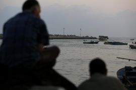 Palestinian men wait for fishermen at Gaza's seaport in Gaza City early on August 29, 2014. Israel and Hamas accepted an Egyptian proposal for a long-term ceasefire in war-torn Gaza on August 26 in a move to end 50 days of bloodshed. Restrictions imposed on Gaza fishermen are to be relaxed, with an immediate extension of the fishing zone to six nautical miles from the shore, to be extended later to 12 miles. AFP PHOTO / MOHAMMED ABED
