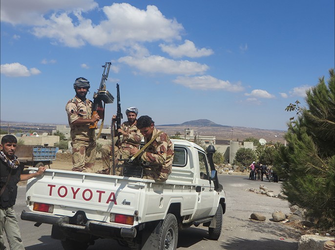 صورة لمقاتلين من درعا في القنيطرة ويظهر وراءهم تل الحارة