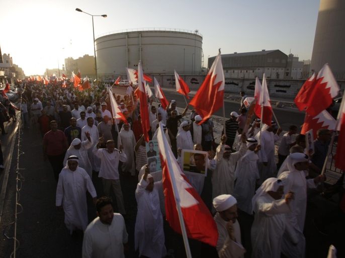 A few thousand Bahrainis wave national flags and carry pictures of political prisoners during a protest march in Sitra, Bahrain, Friday, Sept. 12, 2014. Protesters chanted for democracy in the Gulf island kingdom and freedom for people jailed during the 3 1/2-year-old uprising. (AP Photo/Hasan Jamali)