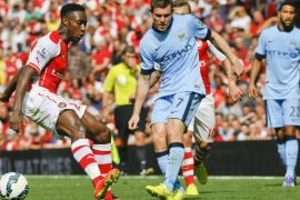 Arsenal's Danny Welbeck, left, vies for the ball with Manchester City's James Milner during the English Premier League soccer match between Arsenal and Manchester City at Emirates Stadium in London, Saturday, Sept. 13, 2014. (AP Photo/Kirsty Wigglesworth)