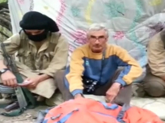 A man who identified himself as Herve Gourdel (C) speaks as he sits in between two masked armed gunmen in this still image taken from video which was published on the Internet on September 22, 2014. The French national was kidnapped in eastern Algeria on Sunday, France's foreign ministry said, and his kidnappers issued a video threatening to kill him if Paris did not halt its intervention in Iraq. The Caliphate Soldiers, a group linked to Islamic State militants, published a video on the Internet soon after the French ministry's announcement on Monday, claiming responsibility for the kidnapping and showing a man who identified himself as Gourdel, 55, from Nice in southern France. The group said it would kill Gourdel if Paris did not halt its intervention in Iraq. The French foreign ministry later confirmed the video was authentic. REUTERS/The Caliphate Soldiers via Reuters TV (CIVIL UNREST CRIME LAW POLITICS) ATTENTION EDITORS - THIS PICTURE WAS PROVIDED BY A THIRD PARTY. REUTERS IS UNABLE TO INDEPENDENTLY VERIFY THE AUTHENTICITY, CONTENT, LOCATION OR DATE OF THIS IMAGE. FOR EDITORIAL USE ONLY. NOT FOR SALE FOR MARKETING OR ADVERTISING CAMPAIGNS. NO SALES. NO ARCHIVES. THIS PICTURE IS DISTRIBUTED EXACTLY AS RECEIVED BY REUTERS, AS A SERVICE TO CLIENTS
