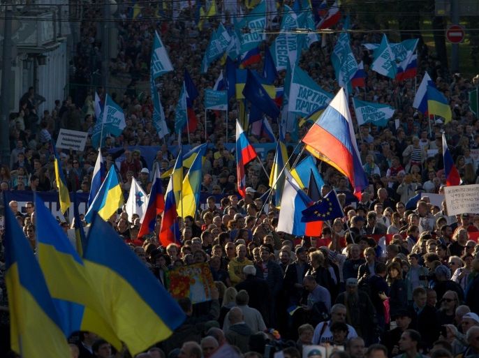 People carry Russian and Ukrainian flags during an anti-war rally in downtown Moscow, Russia, Sunday, Sept. 21, 2014. Thousands of people were marching through central Moscow to demonstrate against the fighting in Ukraine. (AP Photo/Denis Tyrin)