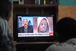 Somali men watch the news on September 6, 2014 in Mogadishu on a television set where is broadcasted a portrait of Somalia's Al-Qaeda-linked Shebab slain leader Ahmed Abdi Godane, recently killed in a US air strike