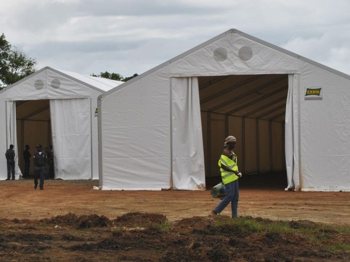 A woman (R) walks at the construction site of an Ebola virus treatment centre at the Samuel K. Doe sports complex in Monrovia September 27, 2014. Liberia has recorded 1,830 deaths, around three times as many as Guinea or Sierra Leone, the two other most affected countries. Nigeria and Senegal have had confirmed cases of Ebola but appear to have prevented it from spreading. REUTERS/James Giahyue (LIBERIA - Tags: HEALTH DISASTER SOCIETY)