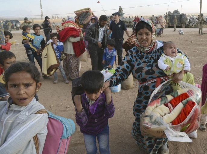Syrian refugees gather at the border in Suruc, Turkey, late Saturday, Sept. 20, 2014. Several thousand Syrians, most of them Kurds, crossed into Turkey on Friday to find refuge from Islamic State militants who have barreled through dozens of Kurdish villages in northern Syria in the past 48 hours. (AP Photo)