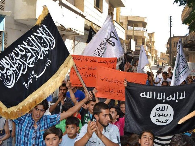 In this photo provided by an anti-Bashar Assad activist group Edlib News Network (ENN), which has been authenticated based on its contents and other AP reporting, anti-Syrian government protesters carry flags of the al-Qaida-affiliated Nusra Front, left, and Islamic State group, right, during a demonstration against the U.S.-led coalition airtstrikes, at Maarat Masrin town, in Idlib province, northern Syria, Friday Sept. 26, 2014. In towns and villages controlled by Syria’s mainstream rebel factions, the airstrikes have garnered mixed reactions. Most people appear to condone hitting the Islamic State group, but question why President Bashar Assad’s forces which have killed thousands of people in the civil war _ remain untouched. (AP Photo/Edlib News Network ENN)