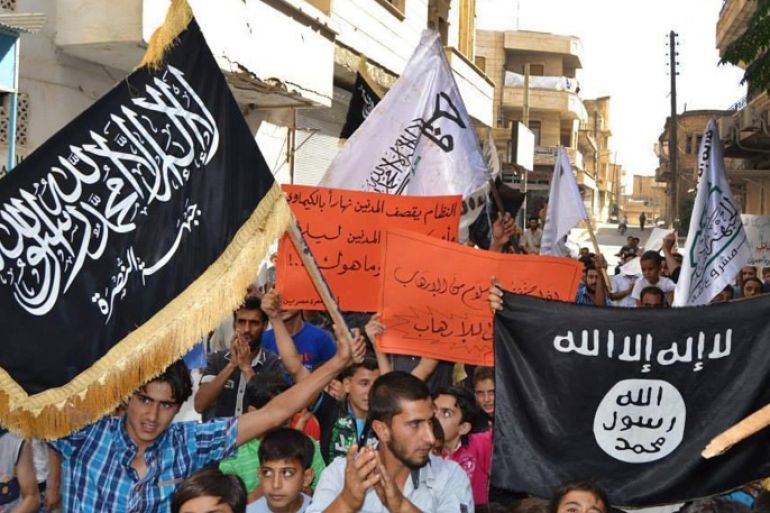 In this photo provided by an anti-Bashar Assad activist group Edlib News Network (ENN), which has been authenticated based on its contents and other AP reporting, anti-Syrian government protesters carry flags of the al-Qaida-affiliated Nusra Front, left, and Islamic State group, right, during a demonstration against the U.S.-led coalition airtstrikes, at Maarat Masrin town, in Idlib province, northern Syria, Friday Sept. 26, 2014. In towns and villages controlled by Syria’s mainstream rebel factions, the airstrikes have garnered mixed reactions. Most people appear to condone hitting the Islamic State group, but question why President Bashar Assad’s forces which have killed thousands of people in the civil war _ remain untouched. (AP Photo/Edlib News Network ENN)