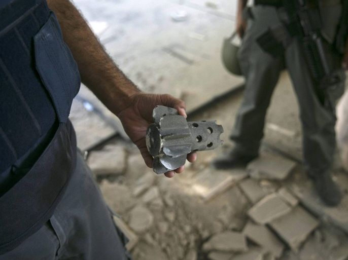 An Israeli police explosives expert shows a remain of a mortar, fired by Palestinian militants in Gaza, after it hit a building in a community outside the central Gaza Strip August 21, 2014. Israel killed three senior Hamas commanders in an air strike on the Gaza Strip on Thursday, the clearest signal yet that Israel is intent on eliminating the group's military leadership after a failed attempt on the life of its top commander this week. After six weeks of conflict in which more than 2,000 Palestinians have been killed, most of them civilians, Israeli air strikes since a 10-day ceasefire collapsed on Tuesday appear to have been focused more intently on Hamas's armed wing. Rocket fire from Gaza continued on Thursday, with several landing in a kibbutz close to the border. Shrapnel from the blast seriously injured one Israeli and narrowly missed a kindergarten, Israel's ambulance service said. REUTERS/Baz Ratner (ISRAEL - Tags: POLITICS CIVIL UNREST CONFLICT)