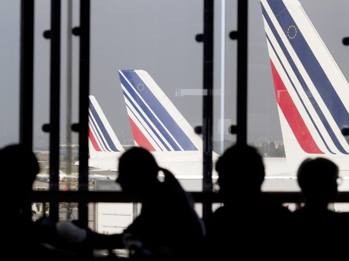 Passengers wait in a lounge as Air France planes are seen behind at Paris-Orly airport on September 15, 2014 in Orly. French flag carrier Air France said it would be forced to scrap half its flights on September 15 as pilots strike in protest at the company's plan to develop its low- subsidiary. AFP PHOTO / KENZO TRIBOUILLARD