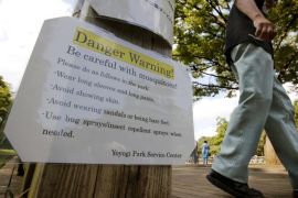 A visitor walks past a mosquitoes warning poster at Yoyogi Park in Tokyo Tuesday, Sept. 2, 2014. Japan is urging local authorities to be on the lookout for further outbreaks of dengue fever, after confirming another 19 cases that were contracted at the popular local park in downtown Tokyo. The cases announced Monday, Sept. 1 raise to 22 the number of dengue infections thought to have been contracted locally. The health ministry earlier reported three local cases, the first in nearly 70 years. Tokyo began spraying Yoyogi park, a vast green area next to Meiji Shrine that is popular with young Japanese and performance artists, after discovering the outbreak. (AP Photo/Shizuo Kambayashi)