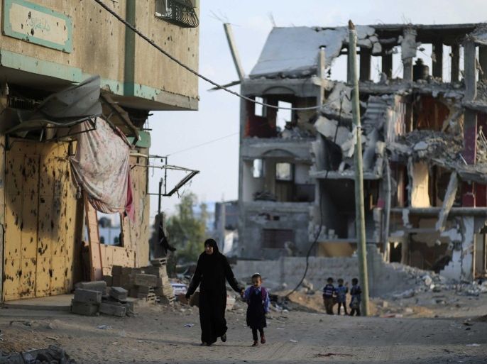 A Palestinian woman walks with her daughter as the remains of a house that witnesses said was destroyed during the 50-day war between the Hamas militant movement and Israel, in the east of Gaza City October 12, 2014. Egyptian President Abdel Fattah al-Sisi urged Israel on Sunday to consider launching new peace efforts based on an Arab initiative first presented in 2002 and rejected by the Jewish state. Sisi was opening a conference in Cairo on rebuilding Gaza after the 50-day war. REUTERS/Mohammed Salem (GAZA - Tags: POLITICS CIVIL UNREST)