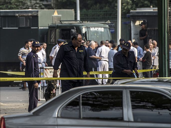 Egyptian policemen and sniffer dogs inspect the site where a bomb exploded outside the main gate of Cairo University on October 22, 2014, wounding at least nine people including a senior officer. The assistant police chief of Cairo's Giza district was moderately wounded, as were six policemen stationed outside the campus to quell protests and three civilian passersby, an interior ministry official said. AFP PHOTO / KHALED DESOUKI