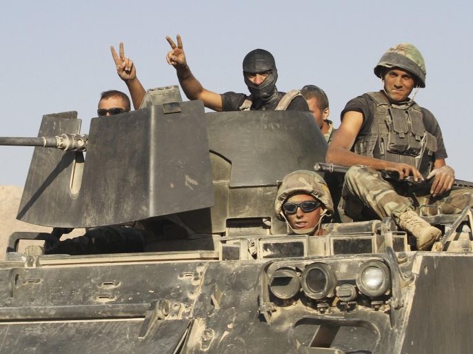 Lebanese army soldiers gesture while riding on an armoured vehicle as they exit the Sunni Muslim border town of Arsal, in eastern Bekaa Valley August 28, 2014. Gunmen killed at least one Lebanese soldier on Thursday when they attacked an army post at the border with Syria on Thursday near a town seized by Islamist insurgents earlier this month, a security source said. Three soldiers were wounded in the clash in the mountainous border zone just outside the town of Arsal, which was held for five days by militants, including fighters affiliated to Islamic State, in an incursion that resulted in deadly battles with the army. REUTERS/Ahmad Shalha (LEBANON - Tags: POLITICS CIVIL UNREST MILITARY)
