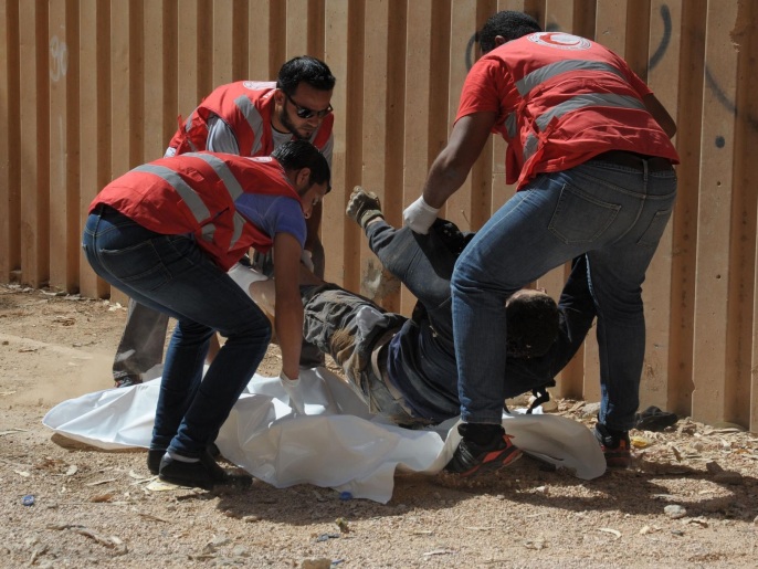 مسعفون ينقلون جثة أحد قتلى الأشتباكات الأخيرة في بنغازي (الفرنسية/غيتي)