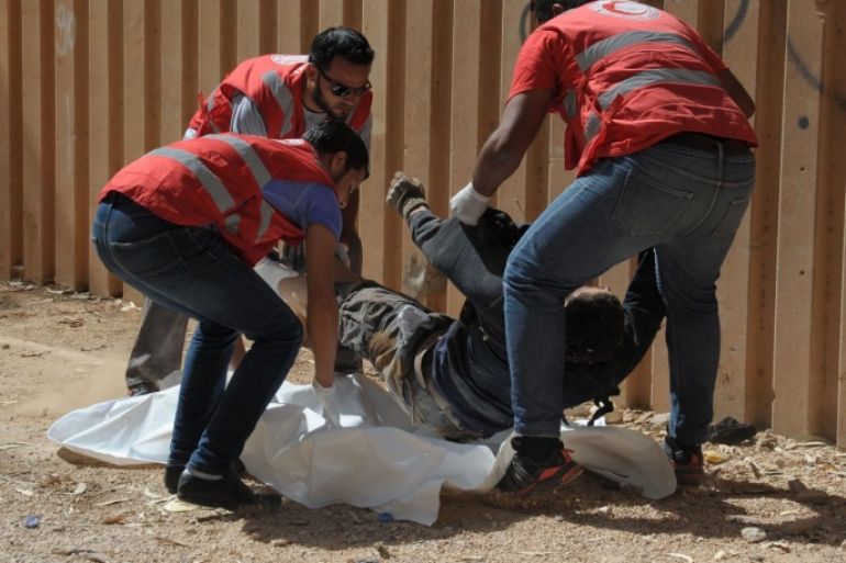 Members of the Libyan Red Crescent remove the body of a man from the street during clashes between soldiers and Islamists who control Benghazi, the country's second biggest city, on October 15, 2014. Libya's army threw its weight behind an ex-general who launched a new assault today to retake Benghazi from Islamist militias who have seized control of large parts of the turmoil-gripped country. AFP PHOTO/STR