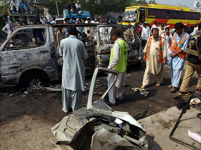 Pakistani volunteers search the wreckage of a passenger van after a bomb explosion in Peshawar on October 2, 2014. A bomb blast on a passenger coach in northwest Pakistan killed at least seven people and wounded another six, police said. The bomb was planted beneath a passenger seat and exploded in the outskirts of Peshawar, the region's main city, while the bus was en route to the town of Hangu. AFP