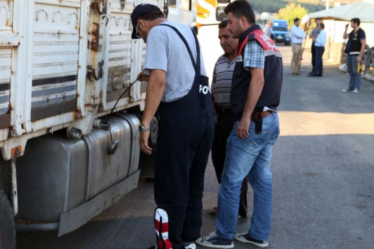 FILE - In this Saturday, Sept. 20, 2014 file photo, Turkish anti-smuggling experts check a truck on a road near Hacipasa, Hatay, Turkey. At the peak of Turkey’s oil smuggling boom, the main transit point was a dusty hamlet called Hacipasa on the Orontes River that marks the border with Syria. Hacipasa has been a smuggling haven for decades, authorities and residents say. The fuel had come from oil wells in Iraq or Syria controlled by militants, including the Islamic State group, and was sold to middle men who smuggled it across the Turkish-Syrian border.(AP Photo/Burhan Ozbilici, File)