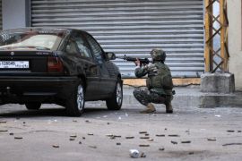 A Lebanese soldier points his weapon taking cover behind a car during clashes with gunmen on October 25, 2014 in the historic area of the northern city of Tripoli. Clashes initially erupted the day before in the souks (traditional markets) area, wounding at least seven Lebanese army troops, three civilians and six Islamist gunmen. Ever since the war in neighbouring Syria broke out in 2011, Tripoli has been the scene of regular fighting between Sunni militants and members of Lebanon's Alawite minority. AFP PHOTO / IBRAHIM CHALHOUB