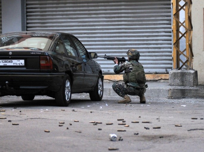 A Lebanese soldier points his weapon taking cover behind a car during clashes with gunmen on October 25, 2014 in the historic area of the northern city of Tripoli. Clashes initially erupted the day before in the souks (traditional markets) area, wounding at least seven Lebanese army troops, three civilians and six Islamist gunmen. Ever since the war in neighbouring Syria broke out in 2011, Tripoli has been the scene of regular fighting between Sunni militants and members of Lebanon's Alawite minority. AFP PHOTO / IBRAHIM CHALHOUB