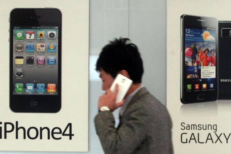 A man walks past banners advertising Samsung and Apple's smartphones at a mobile phone shop in Seoul, South Korea, Friday, Nov. 22, 2013. A Silicon Valley jury added $290 million more to the damages Samsung Electronics owes Apple for copying vital iPhone and iPad features, bringing the total amount the South Korean technology titan is on the hook for to $930 million.(AP Photo/Yonhap, Han Sang-kyun) Korea Out