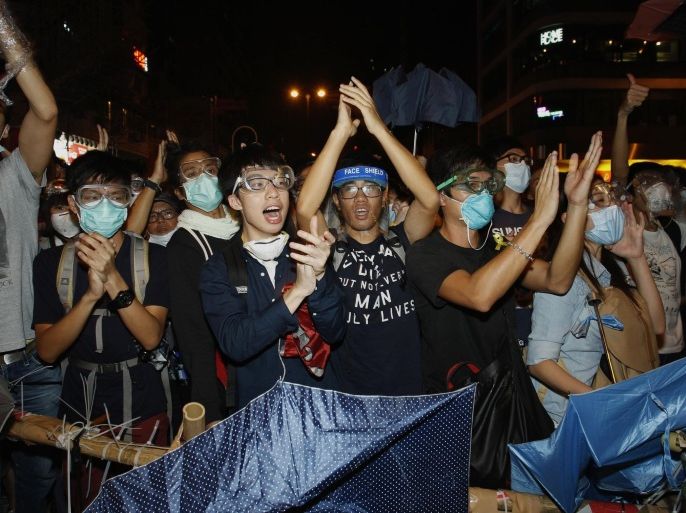 Pro-democracy protesters applaud after riot police retreated from a main road at Mong Kok shopping district in Hong Kong early October 18, 2014. About a thousand Hong Kong pro-democracy activists recaptured parts of a core protest zone early on Saturday, defying riot police who had tried to disperse them with pepper spray and baton charges. REUTERS/Liau Chung-ren (CHINA - Tags: POLITICS BUSINESS CIVIL UNREST CRIME LAW)
