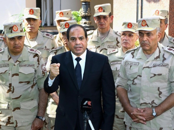 In this photo provided by Egypt's state news agency MENA, Egyptian President Abdel-Fattah el-Sissi, center, speaks in front of the state-run TV ahead of a military funeral for troops killed in an assault in the Sinai Peninsula, as he stands with army commanders in Cairo, Egypt, Saturday, Oct. 25, 2014. El-Sissi appeared on the state-run TV and said a deadly assault on an army checkpoint in the Sinai Peninsula that killed 30 troops was a "foreign-funded operation." No group has yet claimed responsibility for the attack. (AP Photo/MENA, Mohammed Samaha)