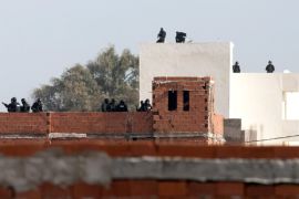 ALTERNATIVE CROP OF TUN106 - Tunisian anti-terrorist police forces (BAT) stand on roofs near a house where suspected Islamist militants were hidden in Raoued, near Tunis, Tuesday, Feb.4, 2014. Tunisia’s National Guard stormed suspected militants in two houses in a seaside suburb of Tunis on Tuesday to end a daylong standoff, and seven radicals and one member of the security force were killed. The firefight began Monday afternoon when National Guard anti-terrorist units surrounded a house believed to contain militants in the Raoued suburb. (AP Photo/Aimen Zine)