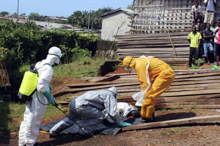 Health workers remove the body a woman who died from the Ebola virus in the Aberdeen district of Freetown, Sierra Leone, October 14, 2014. REUTERS/Josephus Olu-Mammah (SIERRA LEONE - Tags: DISASTER HEALTH SOCIETY TPX IMAGES OF THE DAY)