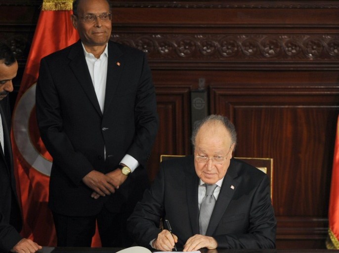 Tunisian president Moncef Marzouki smile as the President of the Tunisian National Constituent Assembly (NCA) Mustapha Ben Jaafar (R) signs a copy of the new constitution after its adoption on January 27, 2014 during a ceremony at the NCA in Tunis. Tunisia's leaders, Marzouki, outgoing premier Ali Larayedh and assembly speaker Mustapha Ben Jaafar, signed the new constitution, a landmark event in the birthplace of the Arab Spring. AFP PHOTO / FETHI BELAID