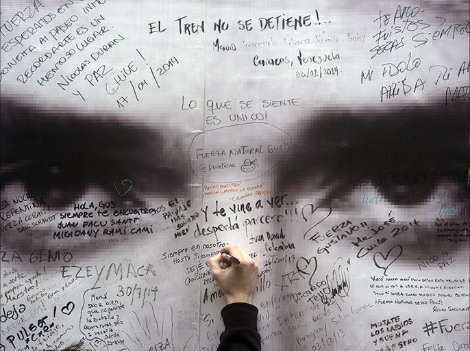 epa04384968 A fan of Argentinean musician Gustavo Cerati writes a message on a poster with his image, in Buenos Aires, Argentina, 04 September 2014. Cerati, leader of the popular Latin American band Soda Estereo, died in Buenos Aires after been in coma for four years due a stroke accident, confirmed the family. EPA