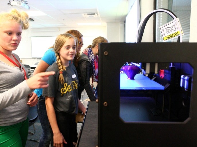 In this Sept. 2, 2014 photo, seventh grader Sydney Scott and sixth grader Jada Waldmann look at the vase in Ron Shaffer's 3D printing class at Maconaquah Middle School in Kokomo, Ind. A mechanical arm repeats the same pattern over and over, dispensing layer after layer of plastic to create the 3-D object designed by Maconaquah Middle School girls in a new enrichment class. (AP Photo/The Kokomo Tribune, Kelly Lafferty)