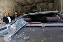 Fayez Abu Eitta (L), a Fatah leader in Gaza, speaks on the phone as he inspects the damage to his car in the parking lot of his home in Beit Lahya, northern Gaza Strip on November 7, 2014. At least 10 explosions hit houses and cars belonging to members of the Fatah movement of Palestinian president Mahmud Abbas in Gaza on Friday, an AFP correspondent and witnesses said. AFP PHOTO / MOHAMMED ABED
