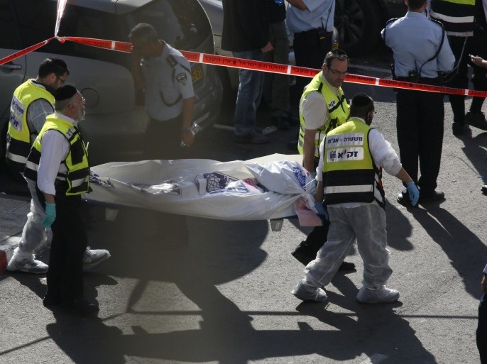 Israeli Zaka emergency services volunteers carry the body of one of the two Palestinian assailants who were shot dead while attacking a synagogue in the ultra-Orthodox Har Nof neighbourhood in Jerusalem on November 18, 2014. The attack, that killed four Israelis, began shortly before 7am (0500 GMT) as worshippers were attending morning prayers. AFP PHOTO / GALI TIBBON