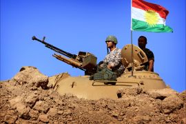 (FILES) - A file picture taken on September 7, 2014, a flag of the autonomous Kurdistan region flies next to Iraqi Kurdish Peshmerga fighters standing on a tank as they hold a position on the front line in Khazer, near the Kurdish checkpoint of Aski kalak, 40 km West of Arbil, the capital of the autonomous Kurdish region of northern Iraq. In Iraq, the battle of security forces, Kurdish troops, Shiite militias and Sunni tribesmen against the Islamic State jihadist group is parallelled by a "war of flags." Banners mark control of territory and identify units as they have for thousands of years, but in this conflict, they also show the sharp religious and ethnic divisions among combatants, including among allies. AFP
