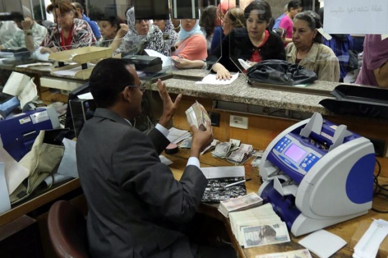 A bank teller receives money from people willing to buy investment certificates for the Suez Canal project at the National Bank of Egypt, in Cairo, Egypt, 08 September 2014. According to media reports, four state-owned banks began on 04 September issuing investment certificates to finance the projects of upgrading the Suez Canal. The new certificates, with values ranging 10 to 1000 Egyptian pounds each (about one to 105 euros), are issued with five years maturity at 12 % annual interest rate. Egyptian authorities on 05 August announced plans for a major upgrade of the 145 years old Suez Canal. The project will involve digging 35 km of a new parallel canal and widening the existing canal along further 37 km.
