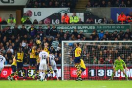 SWANSEA, WALES - NOVEMBER 09: Gylfi Sigurdsson of Swansea City (obscured left) scores their first goal from a free kick during the Barclays Premier League match between Swansea City and Arsenal at Liberty Stadium on November 9, 2014 in Swansea, Wales.