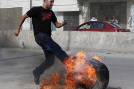 A Palestinian protester kicks a burning tyre during clashes with Israeli troops following an anti-Israel demonstration over the recent entry restrictions to the al-Aqsa mosque, at Qalandia checkpoint near the West Bank city of Ramallah November 2, 2014. A far-right politician who wants Jews to be allowed to pray at Jerusalem's al-Aqsa compound visited the site on Sunday, defying Prime Minister Benjamin Netanyahu's calls for restraint after clashes this week between Israeli police and Palestinians. Sunday was the first day the compound, known to Muslims as Noble Sanctuary and to Jews as Temple Mount, was open to non-Muslims since an Israeli-American activist was shot and seriously wounded after speaking out against the prayer ban. REUTERS/Ammar Awad (WEST BANK - Tags: POLITICS CIVIL UNREST RELIGION)