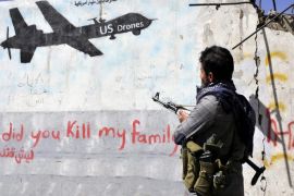 A gunman loyal to the Shiite Houthi movement looks at graffiti protesting US drone operations a day after a US drone killed suspected al-Qaeda in the Arabian Penninsula (AQAP) militants, Sanaa, Yemen, 25 October 2014. Reports state 24 October a US drone strike killed at least ten suspected AQAP militants near the scene of fighting between AQAP and Shiite Houthi fighters in the central Yemeni city of Radaa, which is part of an onoing campaign by the US which has launched at least 92 drone strikes on suspected AQAP militants in Yemen between 2002 and mid-2013, killing hundreds of suspected militants and dozens of civilians.