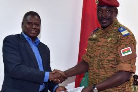Henry Ye, president of the commission representing the main power players (L) hands the transition charter to Burkina Faso's army-appointed leader, Lieutenant-Colonel Isaac Zida during a meeting at the Economic and Social Council headquarters in Ouagadougou, Burkina Faso, on November 14, 2014. Burkina Faso's army on November 13, 2014 reached an agreement with opposition parties, civil groups and religious leaders for a transition to civilian rule, almost two weeks after the ouster of president Blaise Compaore. The different factions 'unanimously voted' in favour of a transition charter, said Henry Ye, president of the commission representing the main power players in the west African country. Under the deal, an interim civilian president will be chosen by a special electoral college, delegates at the talks said. AFP PHOTO / ISSOUF SANOGO