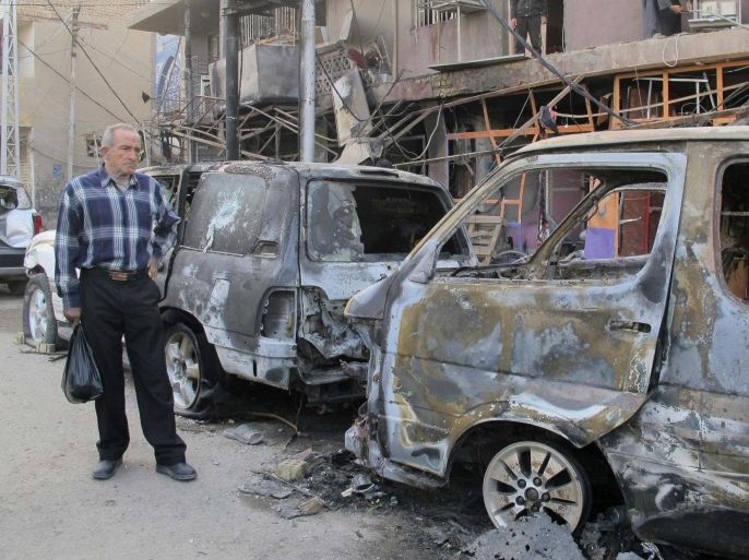 A man looks at the damage at the site of a car bomb attack in Baghdad November 15, 2014. On Friday, two bombs exploded in Baghdad in separate attacks, killing a total of 23 people, police and medical sources said. REUTERS/Stringer (IRAQ - Tags: CIVIL UNREST POLITICS)