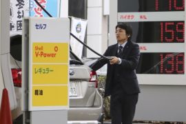 A man puts gas in his car at a Shell filling station with the electric indicator showing a liter of regular gas price, top, at 148 yen, or $1.25, per liter (554 yen, or $4.69 per gallon) in Tokyo Friday, Nov. 28, 2014. A renewed plunge in oil prices is a worrying sign of weakness in the global economy that could shake governments dependent on oil revenues. It is also a panacea as pump prices fall, giving individuals more disposable income and lowering costs for many businesses. Partly because of the shale oil boom in the U.S., the world is awash in oil but demand from major economies is weak so prices are falling. The latest slide was triggered by OPEC’s decision Thursday to leave its production target at 30 million barrels a day. Member nations of the cartel are worried they’ll lose market share if they lower production. (AP Photo/Koji Sasahara)