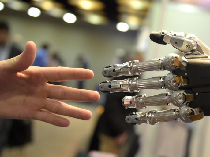 A man moves his hand toward SVH (Servo Electric 5 Finger Gripping Hand) automated hand made by Schunk during the 2014 IEEE-RAS International Conference on Humanoid Robots in Madrid on November 19, 2014. The conference theme 'Humans and Robots Face-to-Face' confirms the growing interest in the field of human-humanoid interaction and cooperation, especially during daily life activities in real environments. AFP PHOTO/ GERARD JULIEN