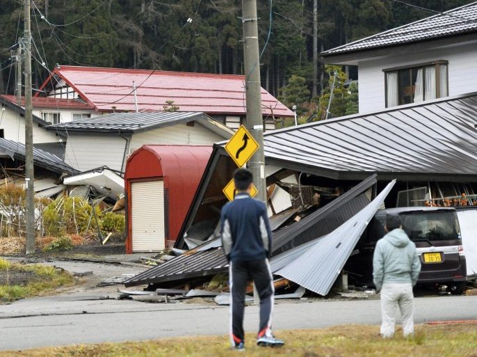 Residents look at houses collasped after a strong earthquake in Hakuba, Nagano prefecture, central Japan, Sunday, Nov. 23, 2014. More than 20 people have been hurt after the magnitude-6.8 earthquake shook on Saturday night the mountainous area that hosted the 1998 winter Olympics. (AP Photo/Kyodo News) JAPAN OUT, CREDIT MANDATORY