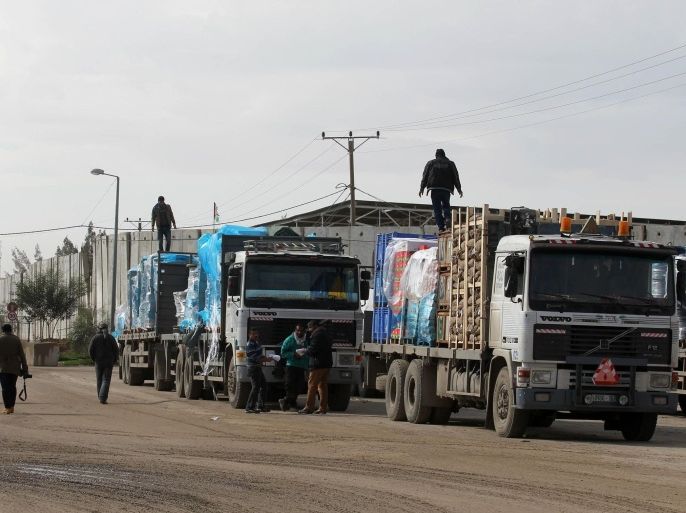 Palestinian men walk past bags of cement loaded on trucks that entered the Gaza Strip from Israel through the Kerem Shalom crossing in Rafah, in the southern Gaza Strip, on November 25, 2014. After the Gaza war ended on August 26, 2014 Israel has allowed a small amount of construction material into Gaza to help rebuild some of the tens of thousands of homes destroyed by air strikes and artillery, but has not palpably eased the blockade. AFP PHOTO / SAID KHATIB