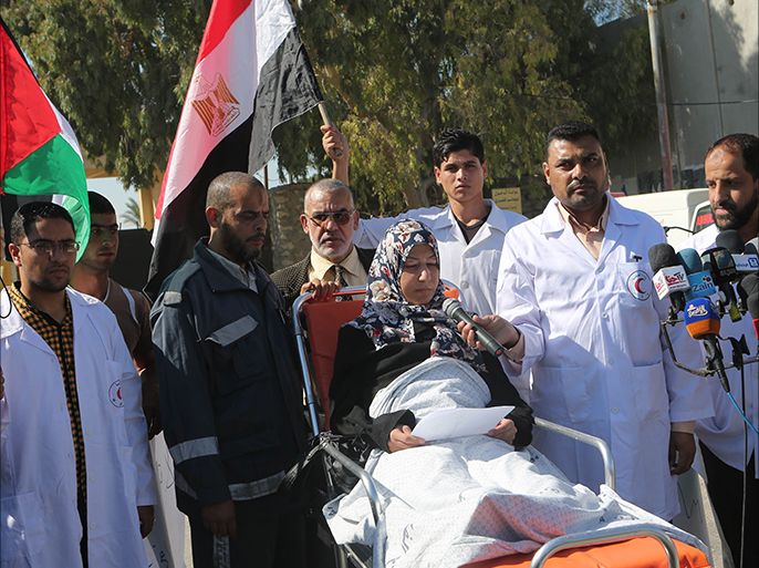 Palestinian medical staff stand next to a patient as she speaks to the media, calling on Egypt to open the Rafah crossing, in front of the Rafah border crossing in the southern Gaza Strip on November 6, 2014. Egypt closed the