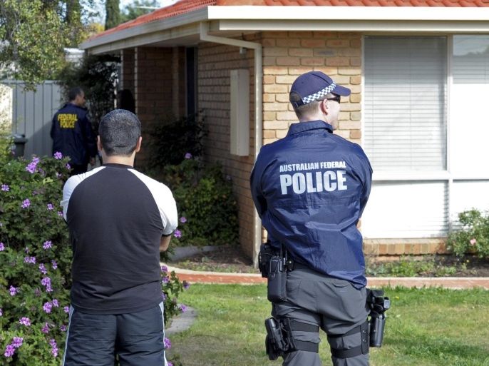 An Australian Federal Police (AFP) officer (R) stands alongside a member of the public at residential premises as part of anti-terrorism raids in Seabrook in Melbourne, Victoria, Australia, 30 September 2014. Police launched anti-terrorism raids across Melbourne on 30 September morning, taking one man into custody. Police said they raided premises in five suburbs with sniffer dogs while helicopters hovered overhead. Police confirmed that search warrants were being enacted as part of a counter-terrorism operation and it added in a statement that the actions were not in response to a threat to public safety. The action was not related to the Melbourne incident last week, where an 18-year-old terrorist suspect was shot dead by police after he attacked two officers with a knife. The raids follow a large operation last week where anti-terrorist police raided homes in Brisbane and Sydney. EPA/JULIAN SMITH AUSTRALIA AND NEW ZEALAND OUT