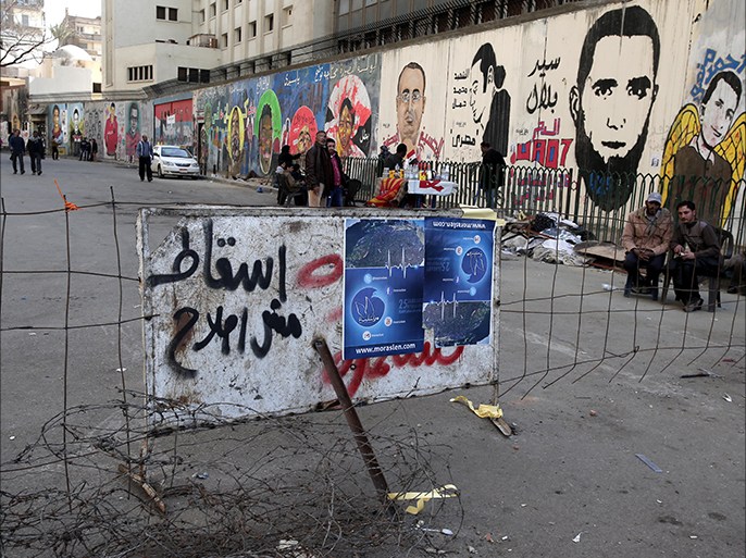 epa03554897 Egyptian protesters sit next to wall-covered graffiti, during a protest marking the second anniversary of the Egyptian revolution, in Mohamed Mahmoud Street, near Tahrir square, in Cairo, Egypt, 25 January 2013. The Egyptian opposition called for rallies on 25 January 2013 against President Mohamed Morsi and his Muslim Brotherhood group, accusing them of tightening their hold on power, on the second anniversary of the revolt that toppled former president Hosni Mubarak on 11 February 2011. EPA/ANDRE PAIN